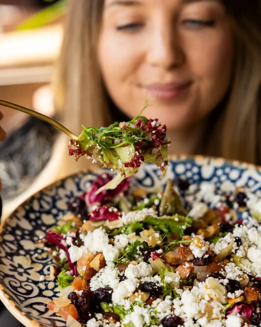 Bunter Salat mit Schafskäse, Cranberrys und Nüssen auf gemustertem Teller
