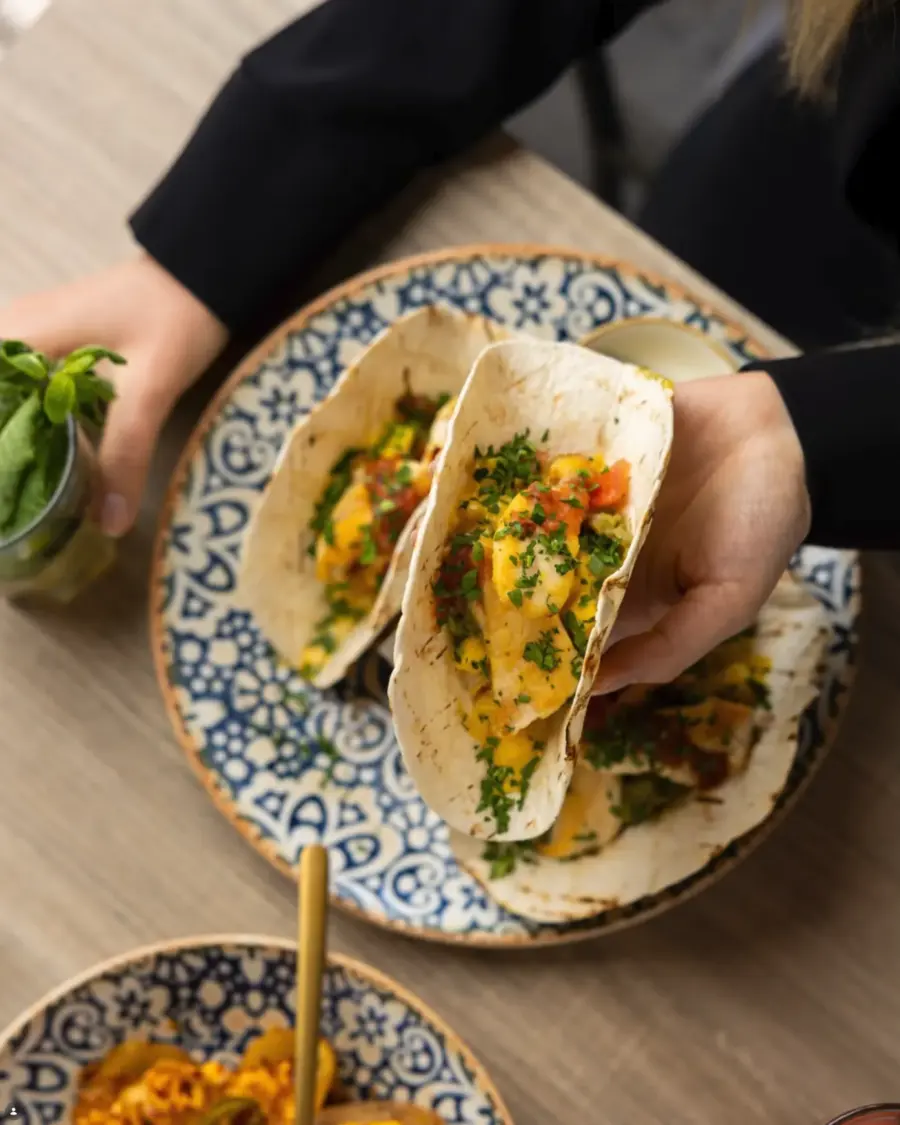 Zwei gefüllte Tacos auf einem blau gemusterten Teller, dazu eine Schale Reis